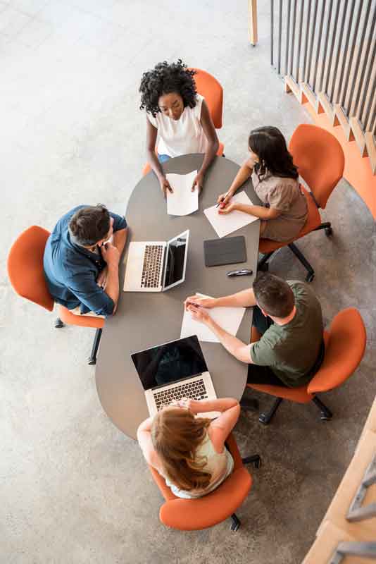 people sitting around a table sitting in orange chairs